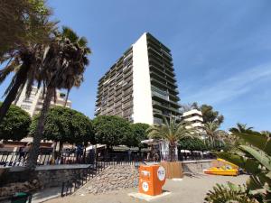 ein hohes Gebäude mit Palmen davor in der Unterkunft Apartamento en primera línea de playa A - Marbella Centro in Marbella
