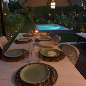 uma mesa com pratos e copos com piscina em Vill'Amar Tróia em Tróia