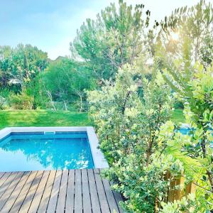 a swimming pool on a wooden deck with trees at Vill'Amar Tróia in Troia