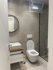uma casa de banho com um WC, um lavatório e um espelho. em 4SeasonsGea , Cozy Studio In Central Position , Tirana em Tirana