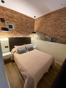 1 dormitorio con 1 cama grande y pared de ladrillo en Apartamentos Rosa La Bonita en Avilés
