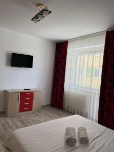 1 dormitorio con 1 cama, TV y cortinas rojas en Apartament Giulia Mamaia Nord en Mamaia-Sat