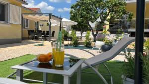 a glass of orange juice on a table with a chair at House Roca in Vodice