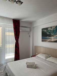 1 dormitorio con 1 cama con cortina roja y ventana en Apartament Giulia Mamaia Nord en Mamaia Nord – Năvodari