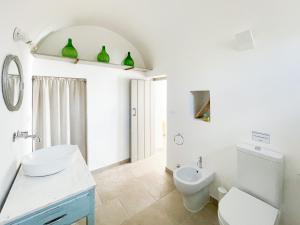 a white bathroom with a toilet and a sink at Trullo San Vincenzo con Piscina in Monopoli +46 photos