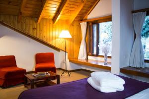 a bedroom with a bed and two chairs and a window at Rincón de los Andes Resort in San Martín de los Andes