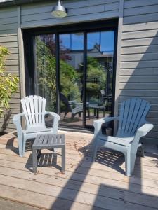 twee witte stoelen en een bank op een veranda bij Le Prevet in Saint-Malo