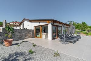 ein Haus mit einer Terrasse mit Stühlen und einer Steinmauer in der Unterkunft Villa Rosemary Trieste HerMes arT in Sežana