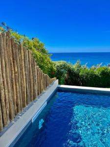 a swimming pool next to a wooden fence and the ocean at Sul Villas & Spa - Azores in Lagoa