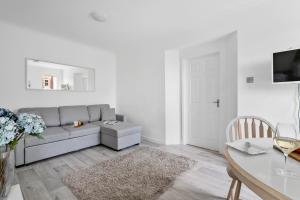 uma sala de estar com um sofá cinzento e uma mesa em Little Place em Torquay