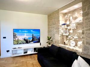 uma sala de estar com uma televisão de ecrã plano numa parede de pedra em Adora Luxury Apartment em Split
