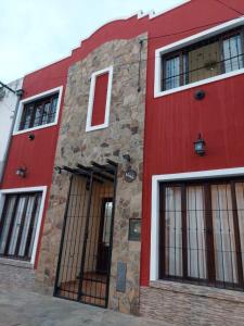 a red building with windows and doors on a street at Hostal Tierra del Sol in Salta