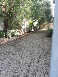 un vialetto di ghiaia con alberi e un edificio di Gli ulivi -Appartamento al centro a Cala Gonone