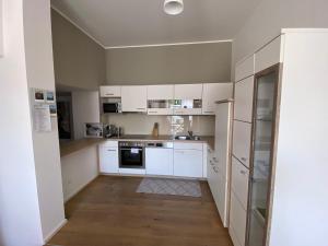 a kitchen with white cabinets and a wooden floor at Adria Villa Apartment family and friends in Velden am Wörthersee