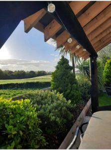 een houten pergola met uitzicht op een tuin bij The Loft at Rock Cottage with hot tub in Garvagh