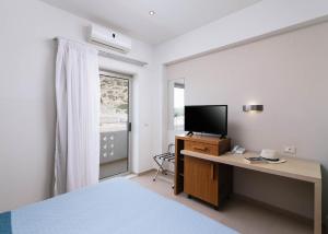a bedroom with a bed and a desk with a television at Matala Bay Hotel in Matala