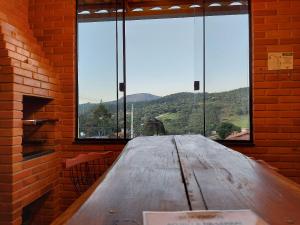Cette chambre dispose d'une table en bois et d'une grande fenêtre. dans l'établissement Villa da Serra chalé Ibitipoca - 700m do centrinho, à Conceição da Ibitipoca