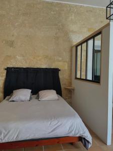 Schlafzimmer mit einem Bett mit einem schwarzen Kopfteil in der Unterkunft Maisonzen in Pugnac