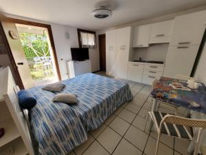 a bedroom with a bed and a table and a kitchen at Alimat Apartment in Lignano Sabbiadoro