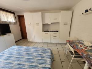 a kitchen with white cabinets and a table in a room at Alimat Apartment in Lignano Sabbiadoro