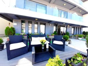 une terrasse avec des chaises bleues, une table et des plantes dans l'établissement Vila Ryanna Beach pe plaja Belona, à Eforie Nord