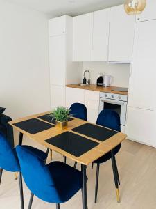 a kitchen with a wooden table and blue chairs at Apartamentai “Viola” Juodkranteje in Juodkrantė +13 photos