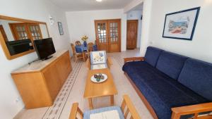 a living room with a blue couch and a tv at Meia Praia in Lagos