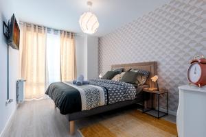 um quarto com uma cama e um relógio em Appartement lumineux de standing em Drancy