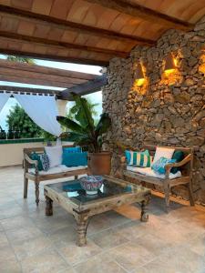 a patio with couches and a table and a stone wall at Finca la Jarra in Benitachell