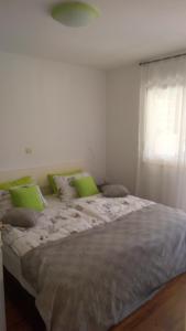 a large bed with green pillows and a window at Apartma Andrea in Medulin