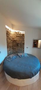 1 dormitorio con 1 cama grande y pared de piedra en Il Gelsomino, en Castelmezzano