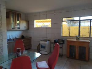a kitchen with a glass table and red chairs at Morada da Lua in Foz do Iguaçu