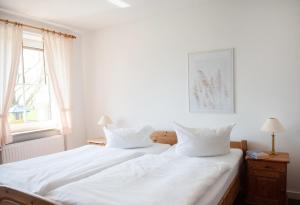 - une chambre avec un lit blanc et 2 oreillers dans l'établissement Bauernhof Höper-Rauert - Reihenhaus 4, à Neujellingsdorf