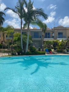 a large swimming pool with palm trees in front of a building at Town House, Ilios II, Kato Paphos in Paphos City