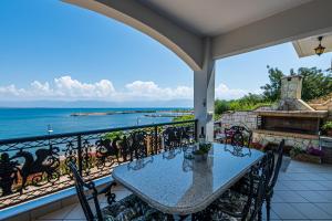 a balcony with a table and chairs and the ocean at Bay View House in Petalidi