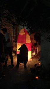 a group of people standing around a lit up umbrella at Porto Sabatiki in Sampatiki