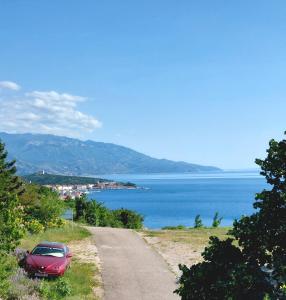 a red car parked on the side of a road at Apartment Boras in Senj