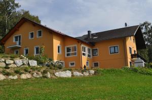ein großes orangenes Haus mit einem Steinzaun davor in der Unterkunft Ferienwohnung Höbart in Dorfstetten