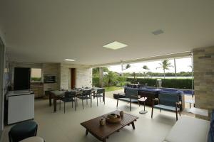 カマサリにあるCasa Luxo Temporada - 5 quartos - Guarajuba - Academia - Piscina e Vistaのリビングルーム(テーブル、椅子付)、大きな窓が備わります。