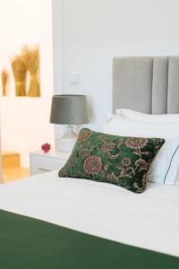 Una cama blanca con una almohada verde. en Casa d'Arcã en Alijó