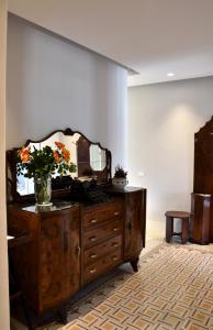 a dresser with a mirror and a vase with flowers on it at Battisti 18 Vintage Rooms in Palermo