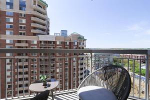 a balcony with two chairs and a table and some buildings at Exquisite 1 Bedroom Condo At Ballston With Gym in Arlington