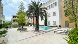 a courtyard with a palm tree and a swimming pool at Porto Montenegro Luxury Studio Zeta in Tivat