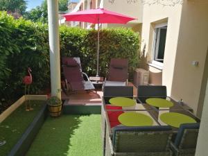 a patio with chairs and an umbrella and grass at Romantisme et glamour 2 avec spa , clim et jardin in Dijon