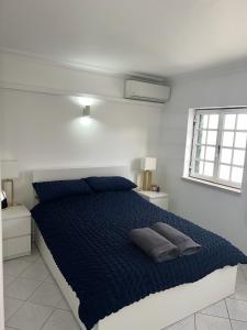 een slaapkamer met een bed met blauwe lakens en een raam bij Relaxing 2 Bedroom House 5 minutes away from Vilamoura Marina in Quarteira