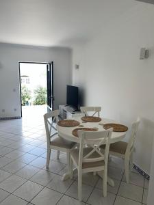 a white dining room with a white table and chairs at Relaxing 2 Bedroom House 5 minutes away from Vilamoura Marina in Quarteira