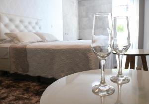 two wine glasses sitting on a table next to a bed at Amber 449 in Gramado