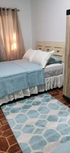 1 dormitorio con 2 camas y alfombra azul en APARTAMENTOS CASCO HISTORICO COMAYAGUA en Comayagua