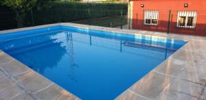 a swimming pool with blue water in front of a building at La Mayor del Viso in Toledo