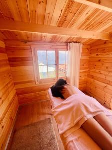 una donna sdraiata in un letto in una stanza di legno di Esprit D'Hotel Panoramico a Fonteno